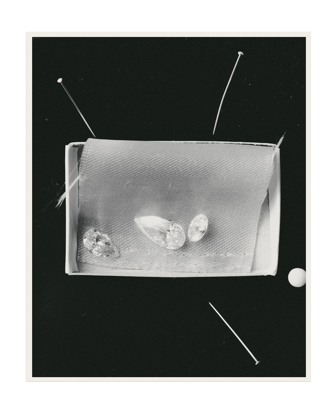 Three loose lab-grown diamonds in pear, oval and cushion cuts displayed in a box with pins, black and white editorial photography – daŭre collection