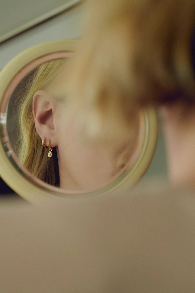 Yellow gold hoop earring with diamond drop seen in mirror reflection - Daure collection