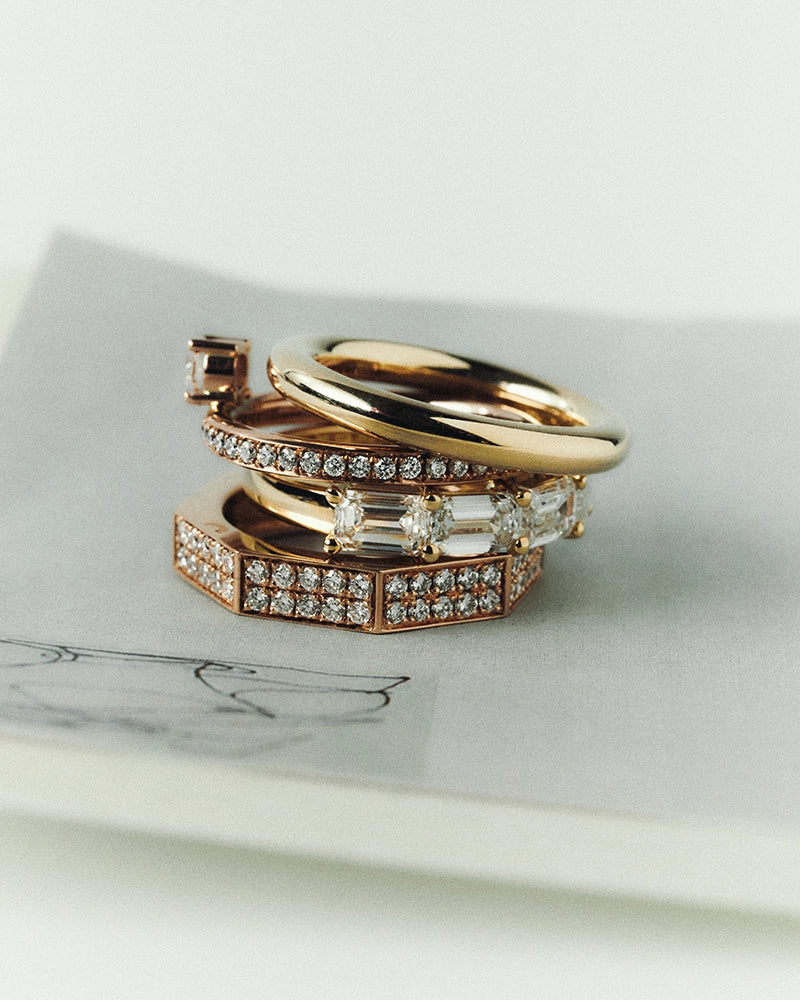 Stack of four rings in yellow and rose gold: octagonal pavé ring, emerald-cut lab-grown diamond band, fine pavé band and polished gold ring – daŭre collection