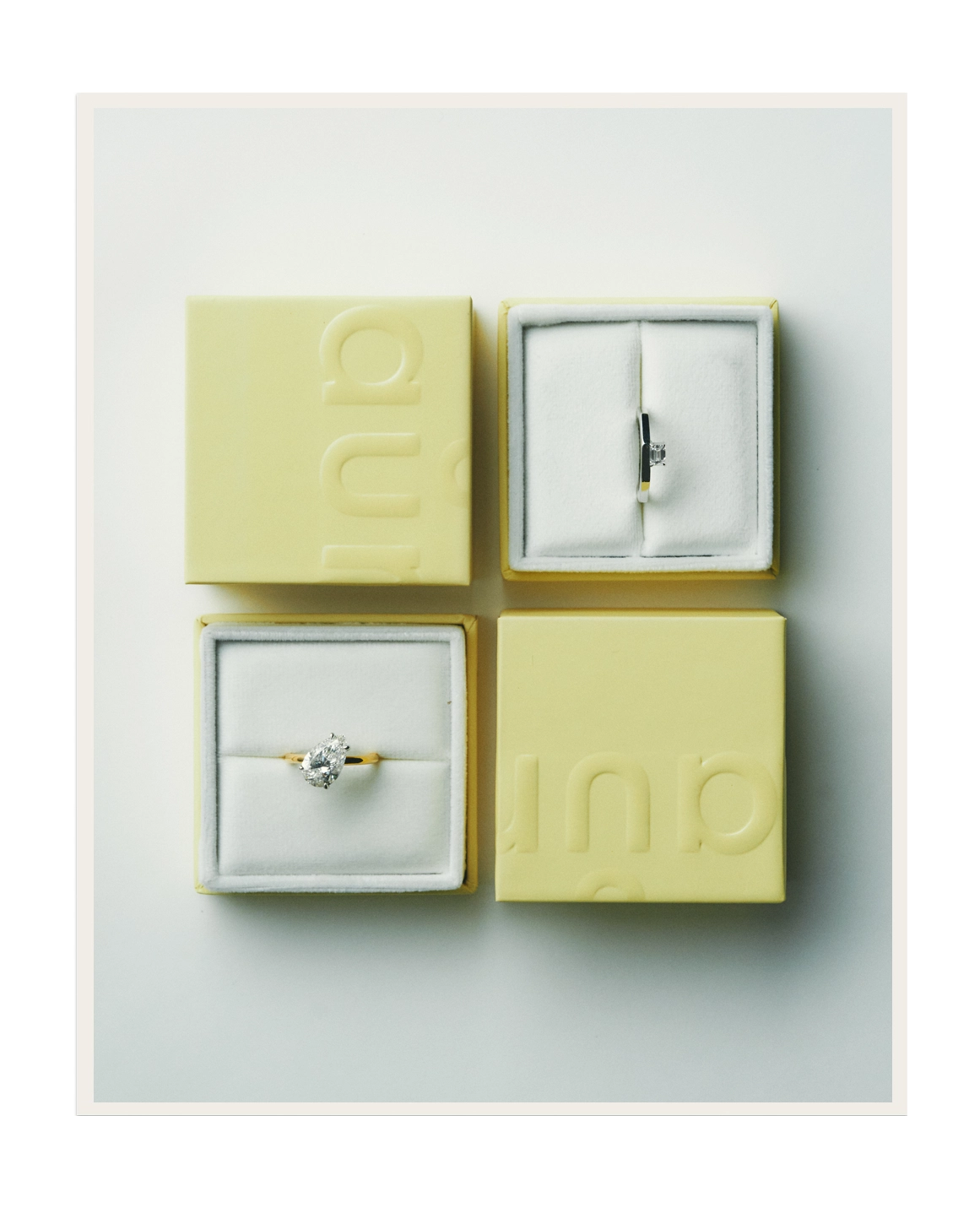 Two lab-grown diamond solitaire engagement rings in yellow gold and white gold, displayed in daŭre signature yellow jewellery boxes – daŭre collection