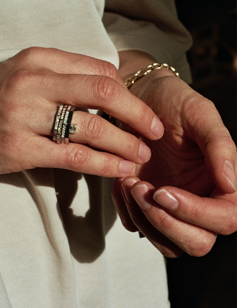 Woman's hands wearing stacked diamond eternity rings with a yellow gold chain bracelet – daŭre collection