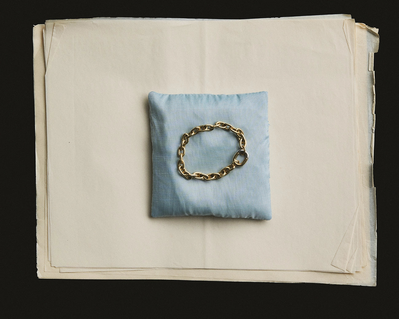 Yellow gold chain link bracelet on blue linen cushion - Daure collection