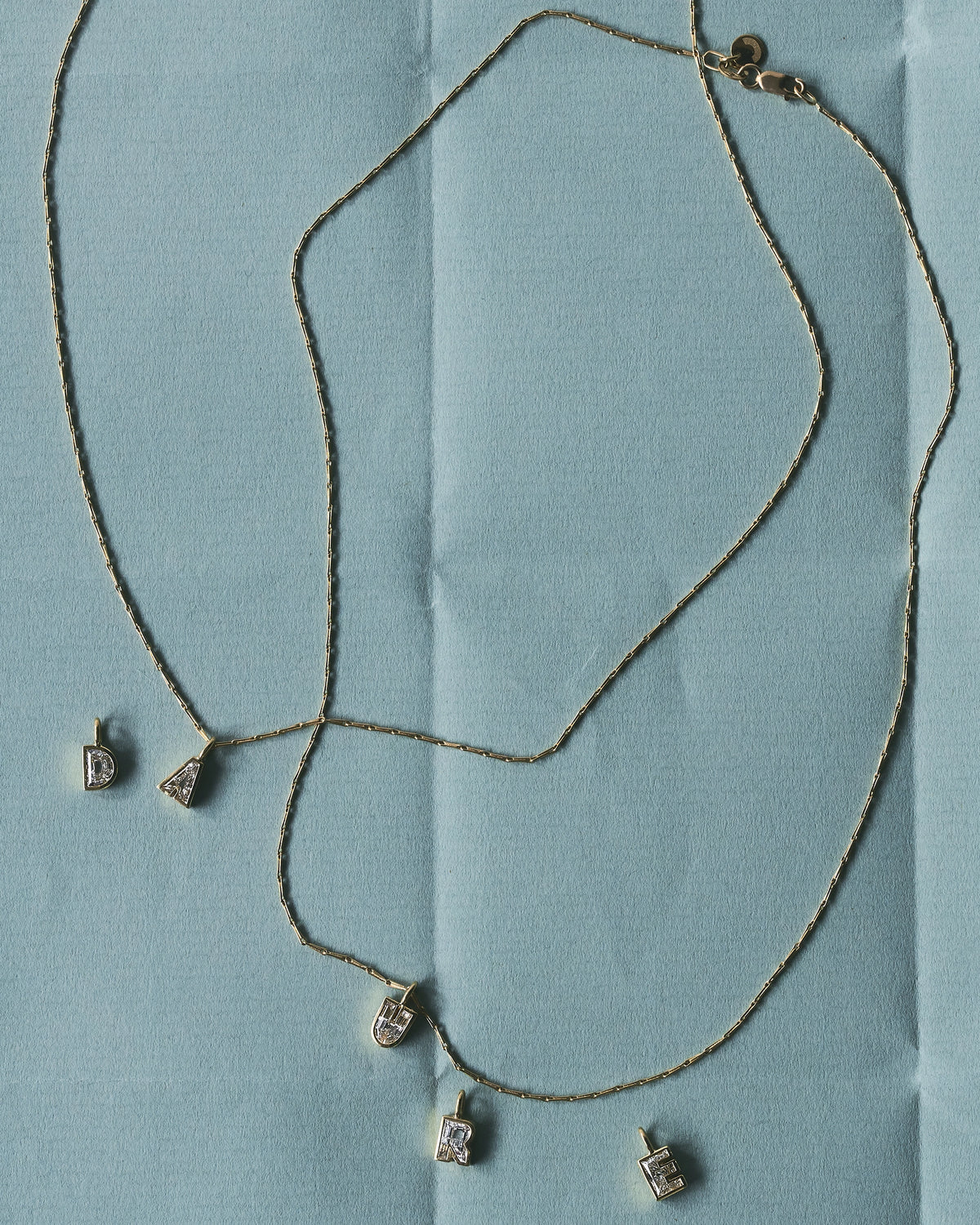 Letera letter pendants in yellow gold with lab-grown diamonds on long layered chains - Daure collection