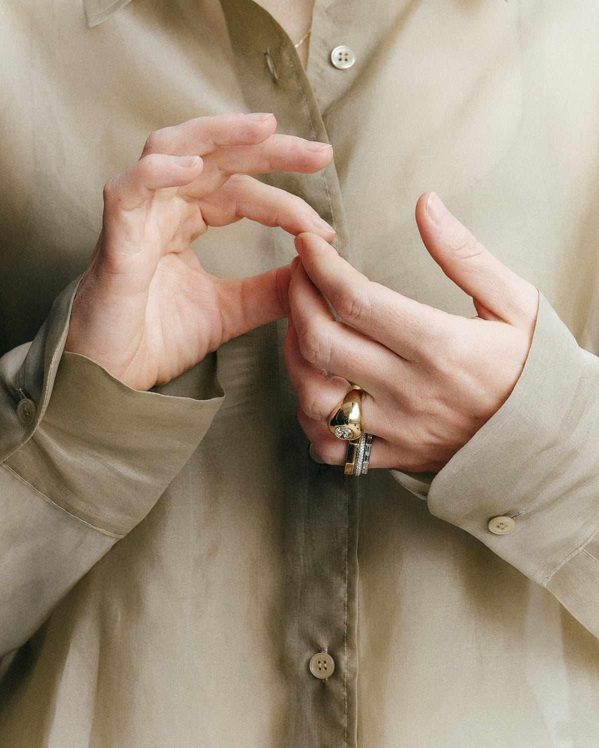 Bague dôme en or jaune sertie d'un diamant de synthèse ovale, portée avec des alliances pavée et baguette - bijoux sur mesure daŭre