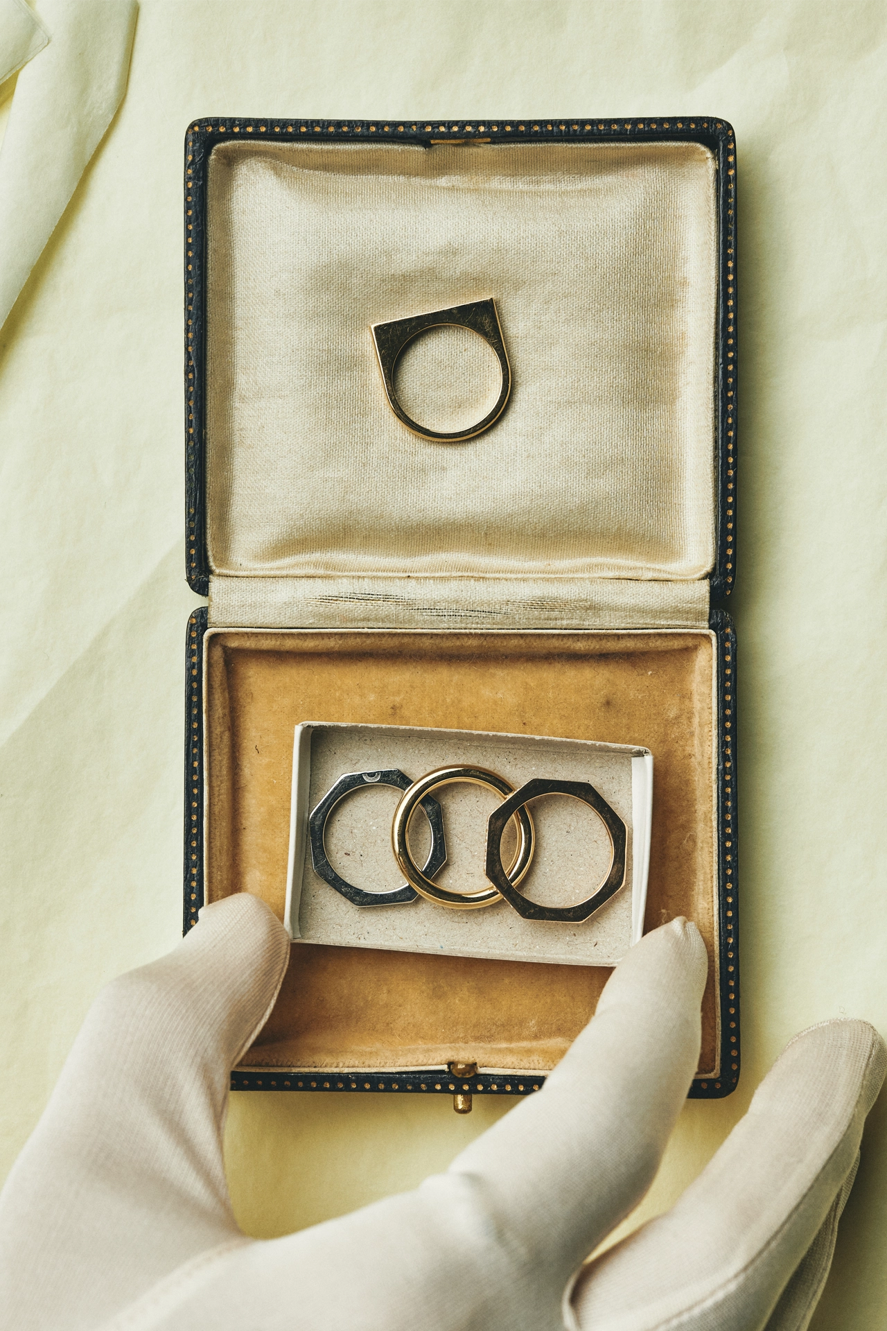 Yellow gold signet ring with octagonal stacking rings displayed in vintage jewelry box, held by gloved hands - Daure collection