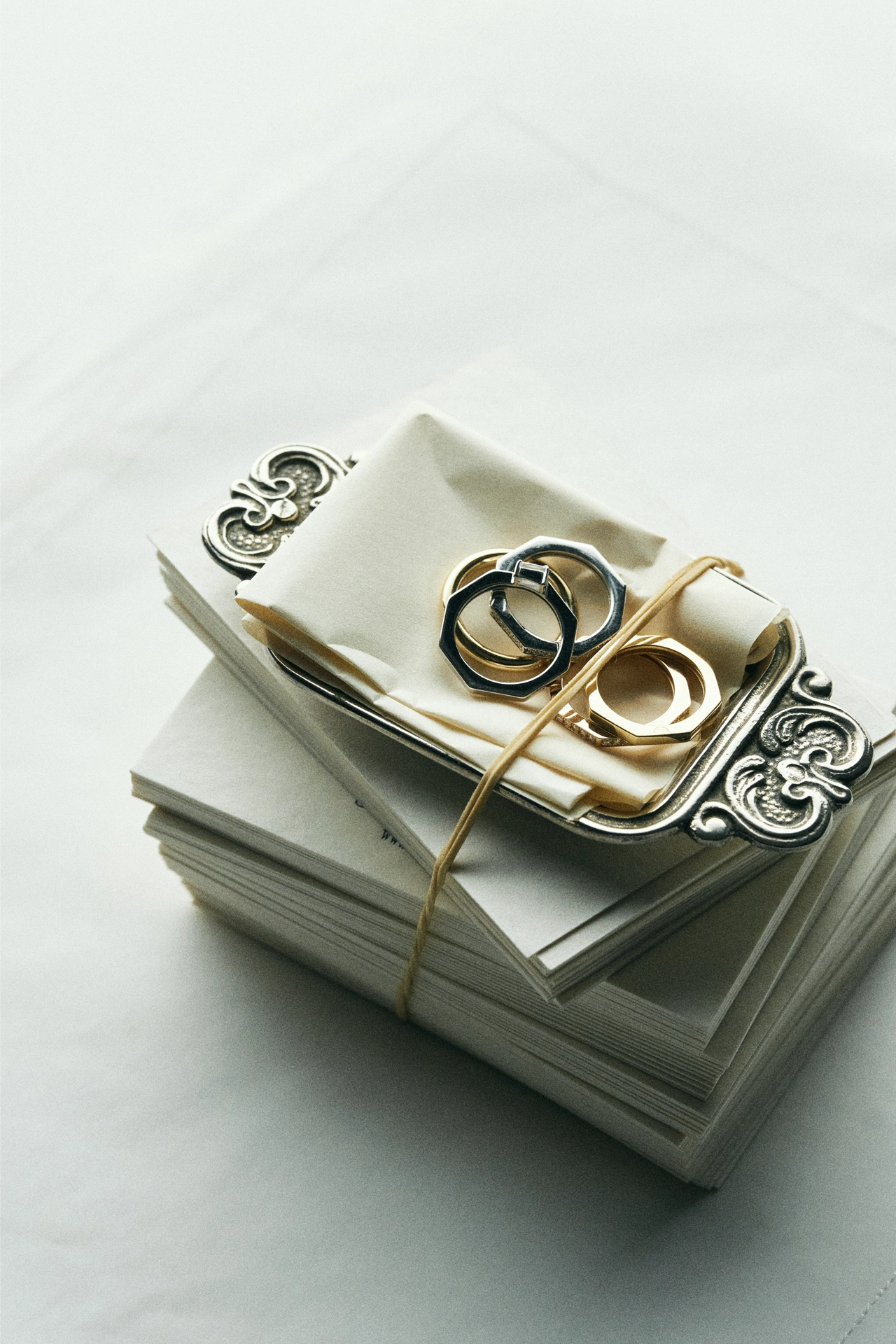 Yellow gold and white gold stacked rings displayed on a vintage ornate tray with bundled letters - Daure collection