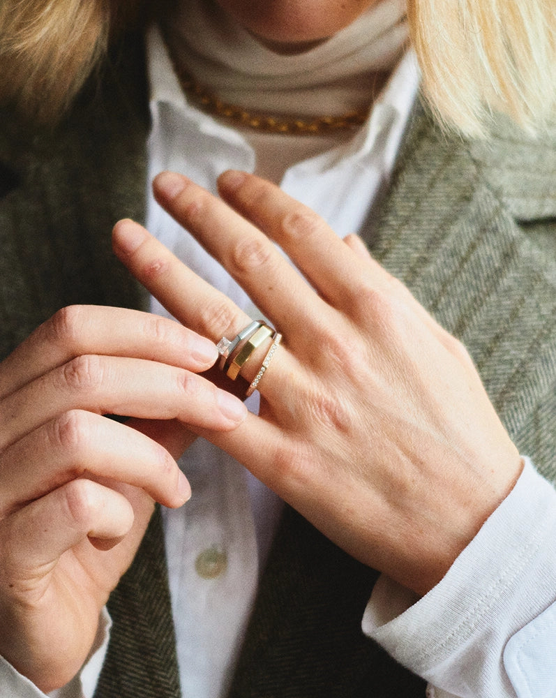 Woman wearing a wide yellow gold band ring, stacked styling - Daure Collection