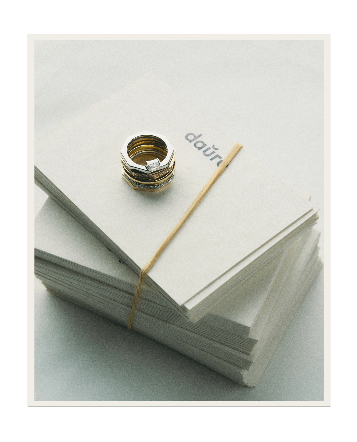 Gold ring on a stack of white papers with 'daria' branding.